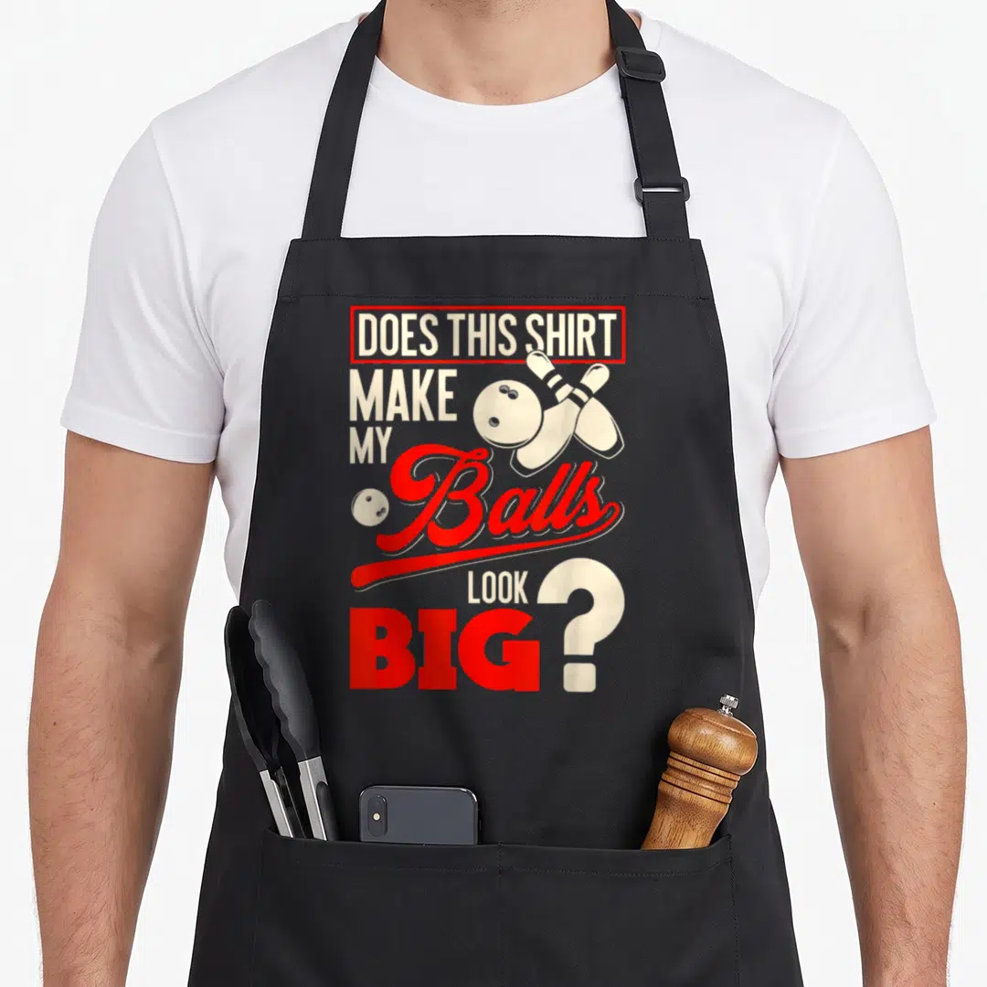 Ball bowling apron - Red and white text DOES THIS SHIRT MAKE MY Balls LOOK BIG with crossed pins and bowling balls — shown on a black cotton canvas apron against a white background