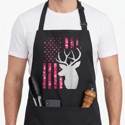 Flag camouflage camo aprons - Pink camouflage US flag stripes with grey deer head silhouette on black bib — shown on a black cotton canvas apron against a white background