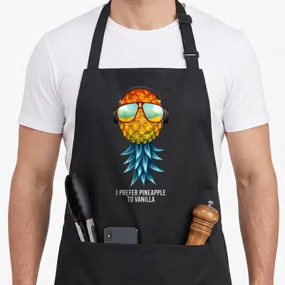 Prefer pineapple apron - Cartoon pineapple with blue leaves, red sunglasses reflecting a beach, and stacked white text — shown on a black cotton canvas apron against a white background