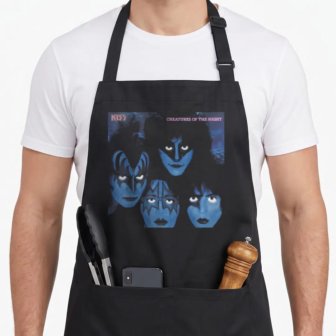 Creature band apron - Four blue-tinted faces with makeup and pink CREATURES OF THE NIGHT text — shown on a black cotton canvas apron against a white background