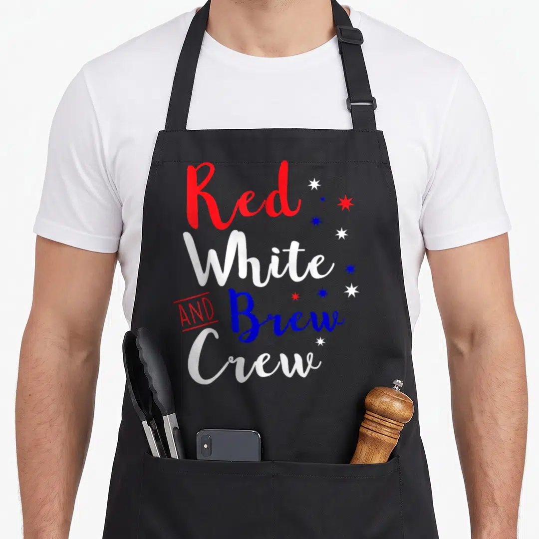Crew 4th of july apron - Red white and brew crew text with eight scattered stars in red white and blue typography — shown on a black cotton canvas apron against a white background