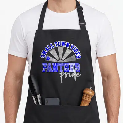 Blue pride apron - SMALL TOWN VIBES text over grey sunburst with PANTHER lettering and blue paw print — shown on a black cotton canvas apron against a white background