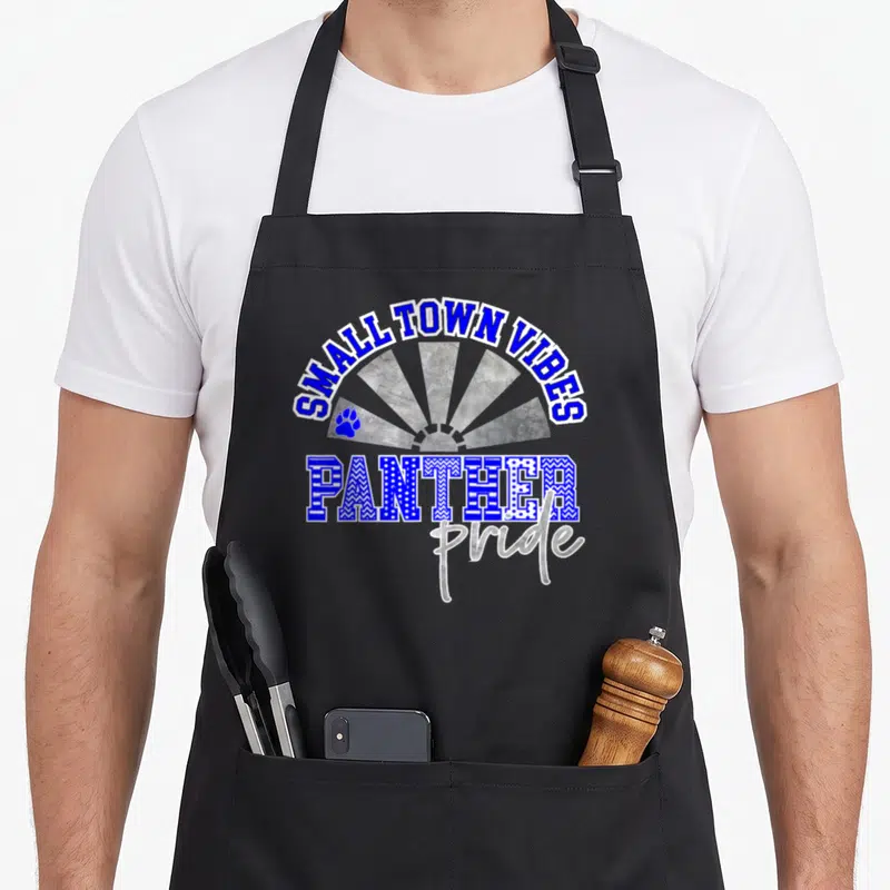 Blue pride apron - SMALL TOWN VIBES text over grey sunburst with PANTHER lettering and blue paw print — shown on a black cotton canvas apron against a white background