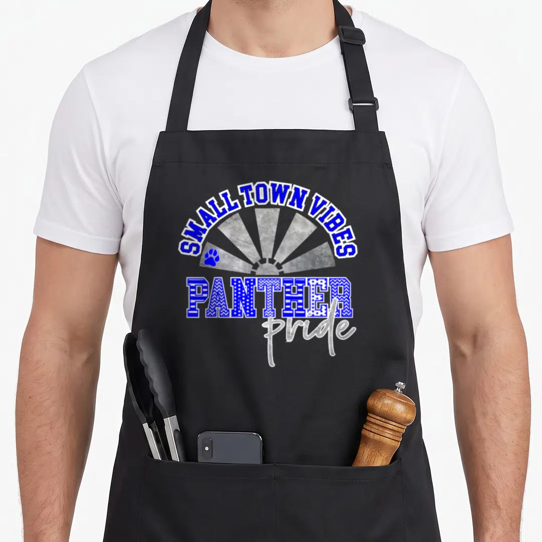 Blue pride apron - SMALL TOWN VIBES text over grey sunburst with PANTHER lettering and blue paw print — shown on a black cotton canvas apron against a white background