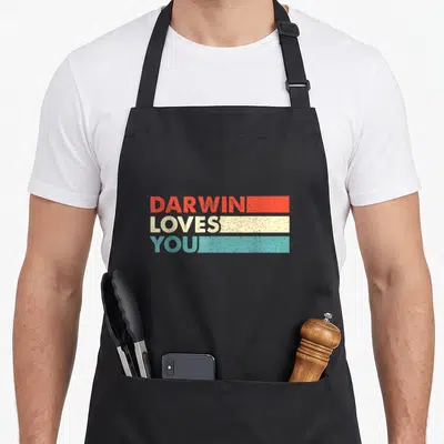 Follower science apron - Stacked DARWIN LOVES YOU text in red cream teal rectangular bars — shown on a black cotton canvas apron against a white background