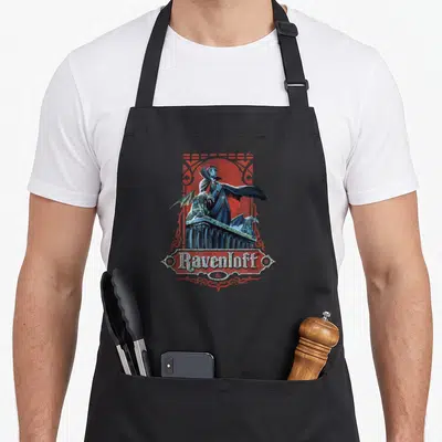 50th dungeon apron - Vampire behind stone balustrade with two gargoyles and Ravenloft & text in red ornamental frame — shown on a black cotton canvas apron against a white background