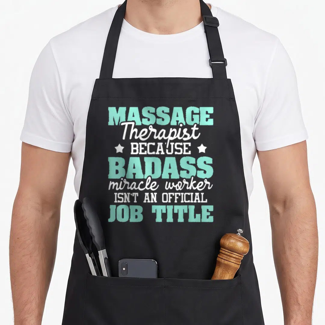 Massager massage therapy apron - Mint and white text reading MASSAGE Therapist BADASS miracle worker with two stars — shown on a black cotton canvas apron against a white background