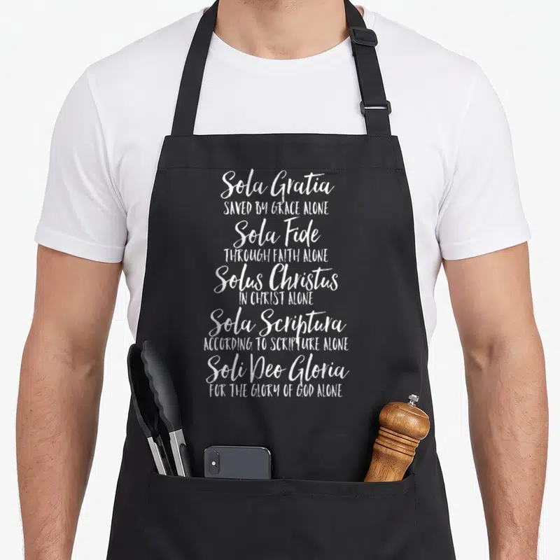 Five english apron - White stacked typography listing Sola Gratia, Sola Fide, Solus Christus, Sola Scriptura, and Soli — shown on a black cotton canvas apron against a white background