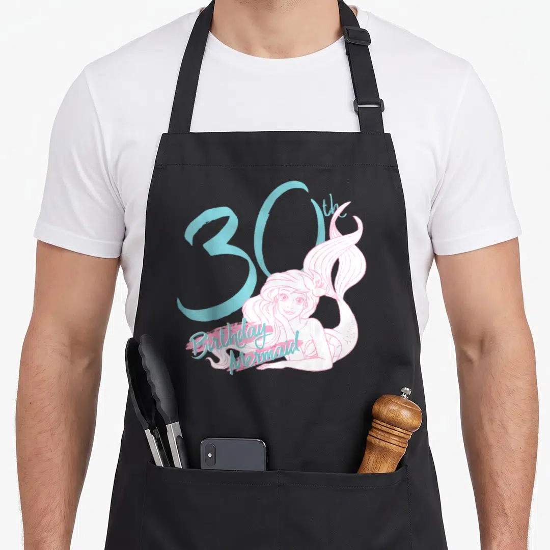Ariel birthday apron - Pink mermaid illustration overlapping a large blue 30 with birthday text below — shown on a black cotton canvas apron against a white background