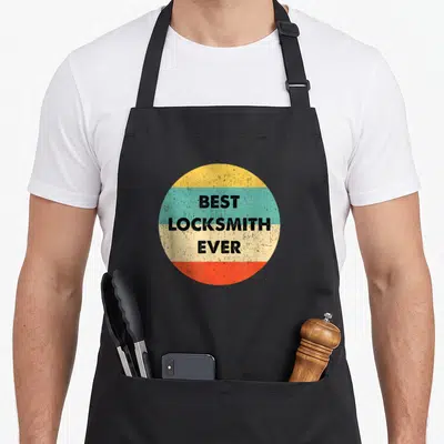 Vintage locksmith squad apron - Retro circle with yellow teal beige and red horizontal bands containing black text BEST — shown on a black cotton canvas apron against a white background
