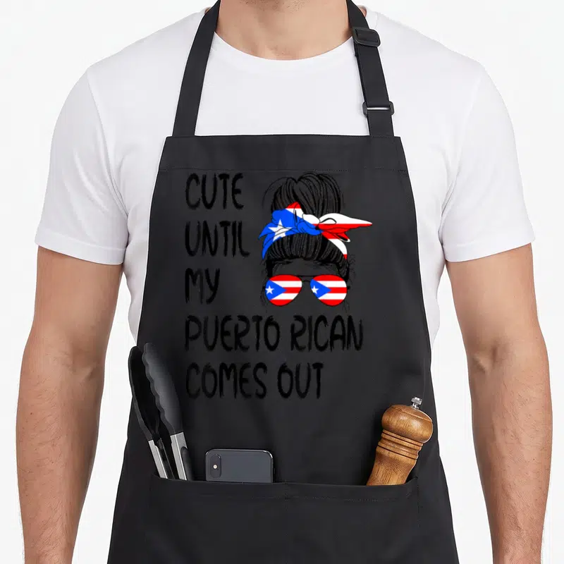 Rican puerto boy apron - Stacked text next to woman with flag sunglasses and bun in line art — shown on a black cotton canvas apron against a white background