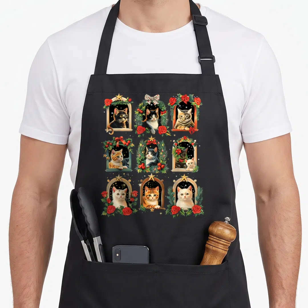 Vintage kitten christmas cat apron - Nine realistic cats in gold arches and wreaths with red roses and green pine — shown on a black cotton canvas apron against a white background