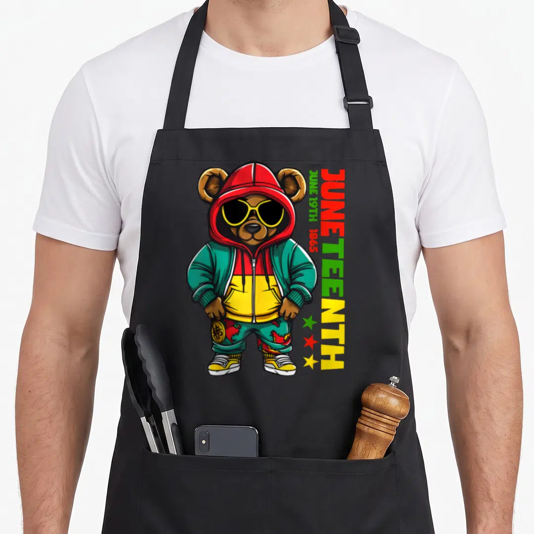 Juneteenth teddy bear apron - Cartoon bear in red yellow green teal streetwear with vertical JUNETEENTH text and three — shown on a black cotton canvas apron against a white background