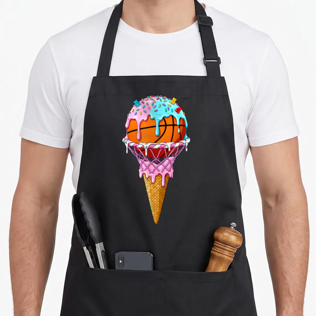Hoop ice cream apron - Cartoon basketball inside hoop and waffle cone with pink blue frosting and gummy bears — shown on a black cotton canvas apron against a white background