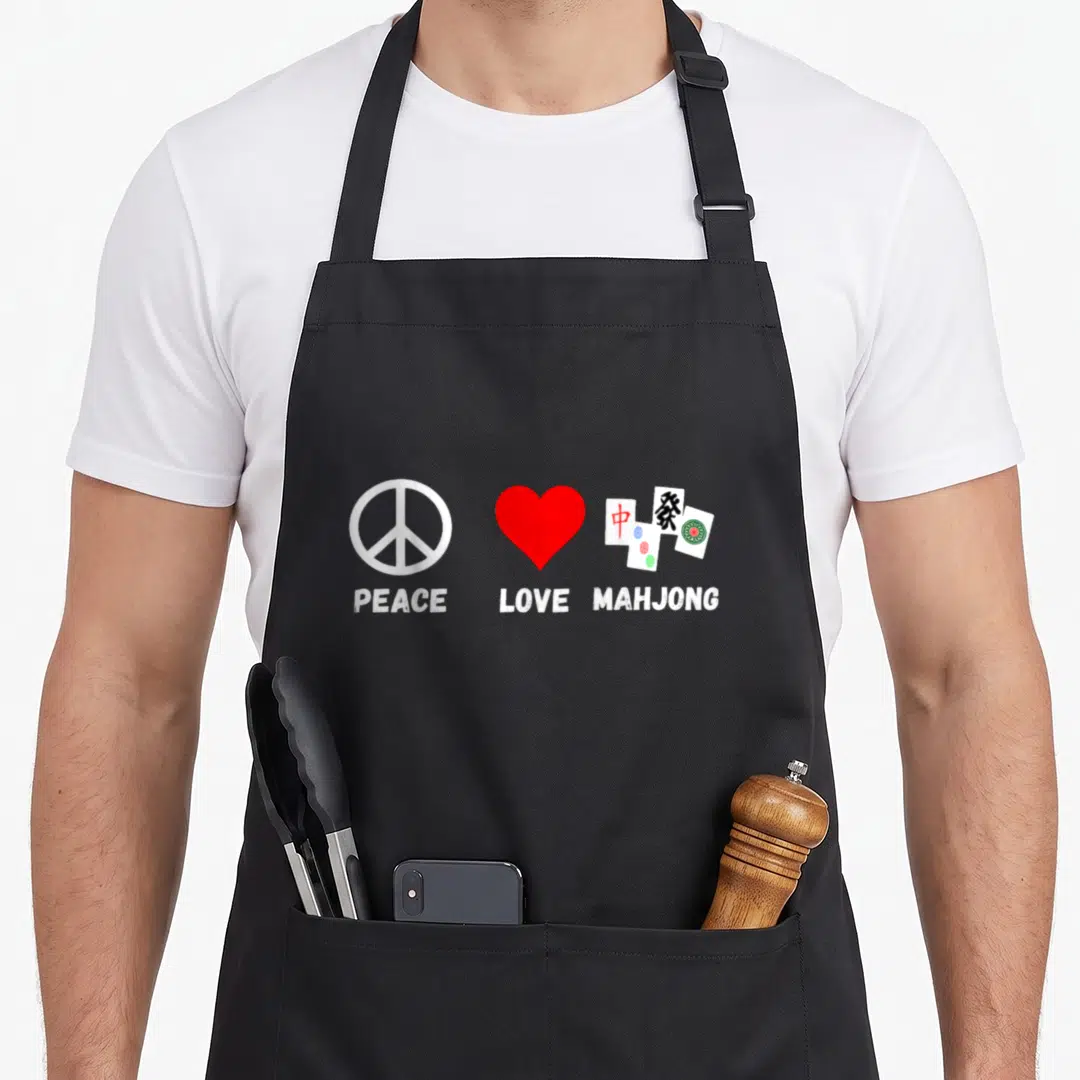 Peace mahjong apron - Three symbols: white peace sign, red heart, and mahjong tiles with text below each in white — shown on a black cotton canvas apron against a white background