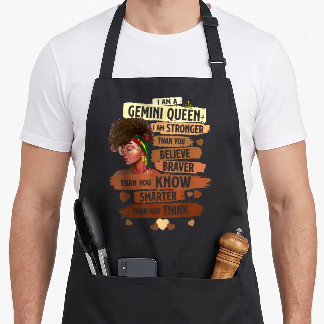 Gemini candy aprons - Woman with afro and glasses beside brown and orange banners reading I Am A Gemini Queen — shown on a black cotton canvas apron against a white background