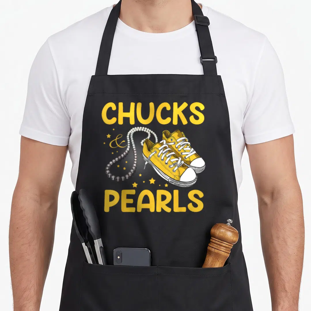 Vintage chuck pearls apron - Yellow sneakers and pearl necklace flanked by CHUCKS and PEARLS text with stars — shown on a black cotton canvas apron against a white background