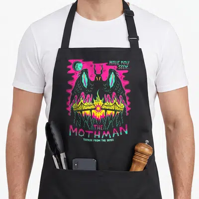 Mothman halloween witch apron - Retro Mothman figure in grey pink cyan yellow over burning bridge with warning text — shown on a black cotton canvas apron against a white background