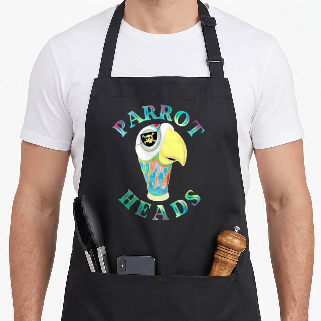 Parrot creative apron - Cartoon parrot head with skull eyepatch and arched multicolor text — shown on a black cotton canvas apron against a white background