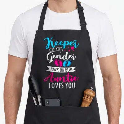 Keeper aunt apron - Stacked text Keeper of Gender with pink and blue footprints and white ribbon banner — shown on a black cotton canvas apron against a white background