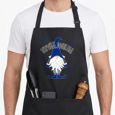 Christmas scandinavian aprons - Cartoon gnome with blue hat and HYVÄÄ JOULUA text surrounded by snowflakes — shown on a black cotton canvas apron against a white background
