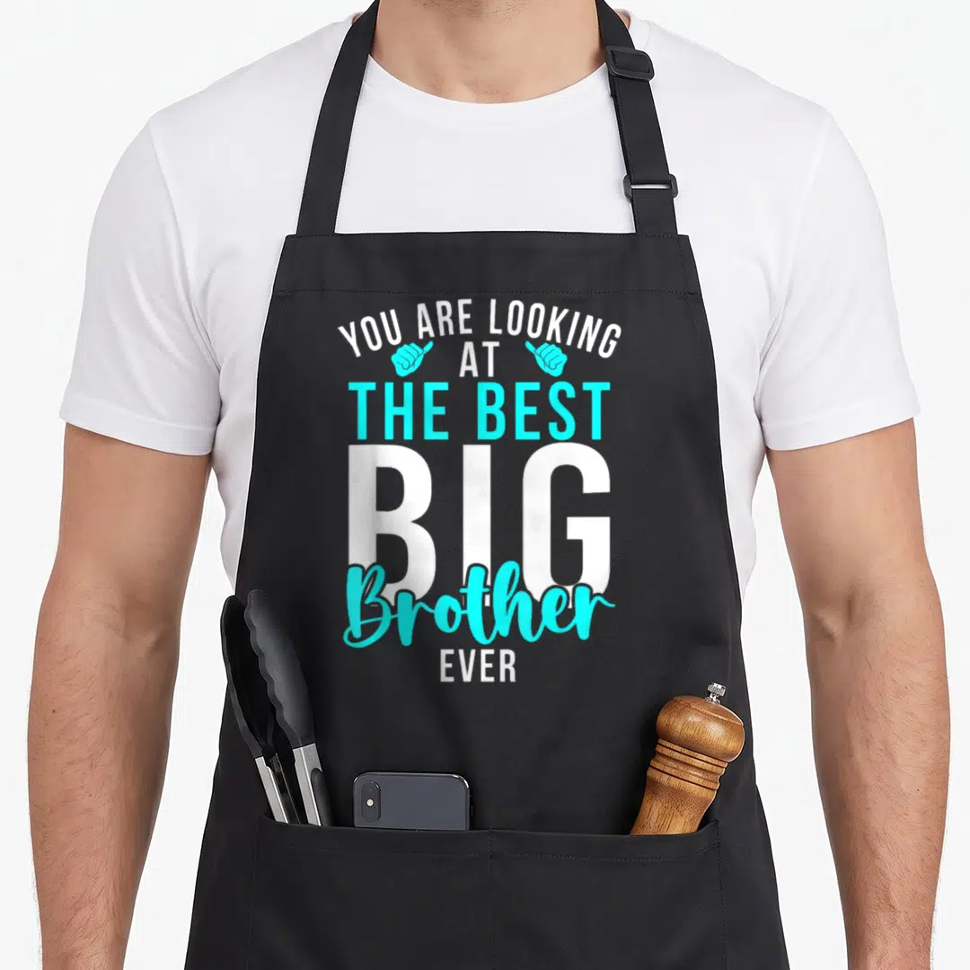 Retro brother apron - Stacked white and cyan text reading YOU ARE LOOKING AT THE BEST BIG Brother EVER with two — shown on a black cotton canvas apron against a white background