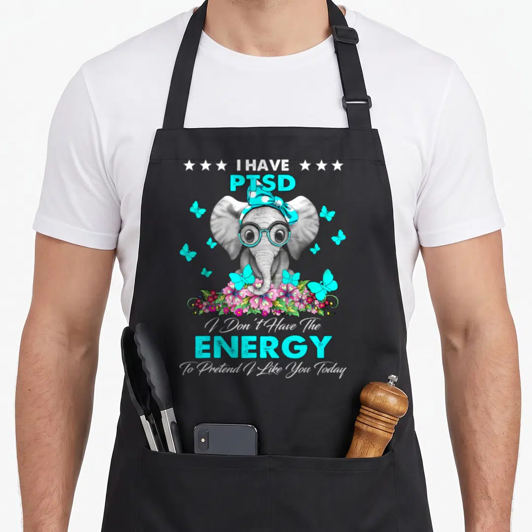 Elephant ptsd awareness apron - Grey elephant with cyan glasses and pink flowers next to I Have PTSD text — shown on a black cotton canvas apron against a white background