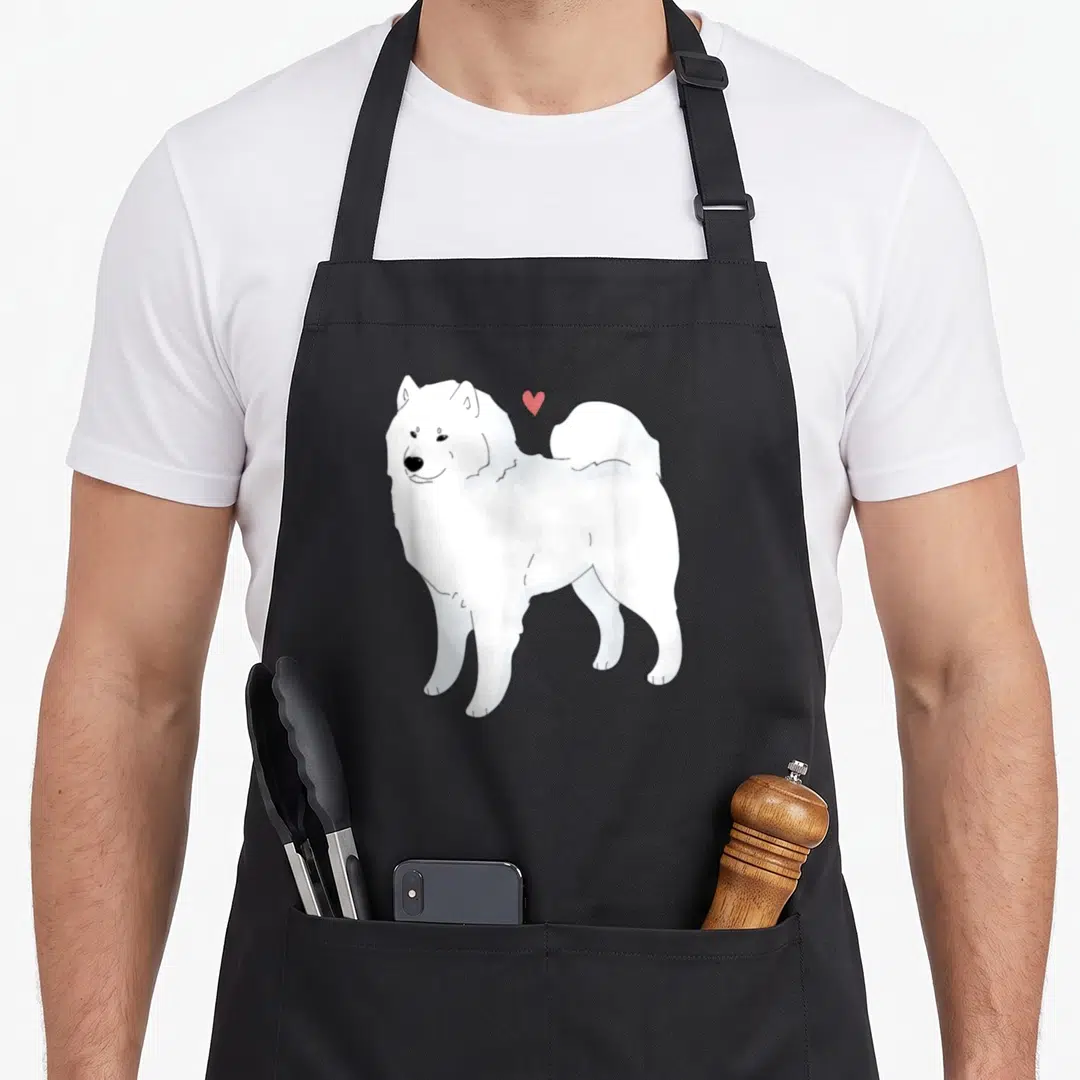 Sammy dog apron - White cartoon Samoyed dog standing with small red heart floating above head — shown on a black cotton canvas apron against a white background