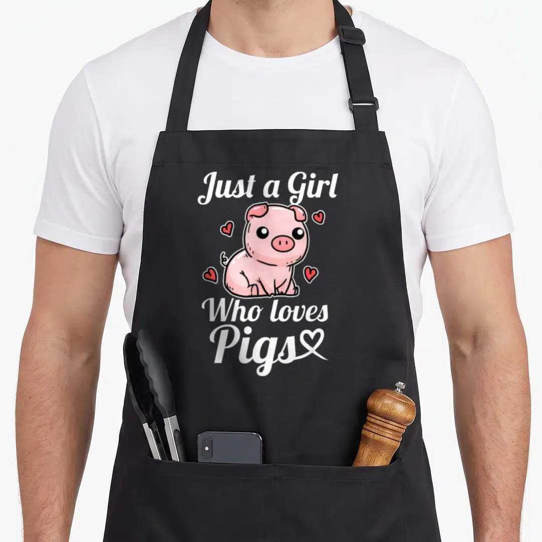 Costume crazy pig lady apron - Cartoon pink pig with white text Just a Girl Who loves Pigs and four scattered hearts — shown on a black cotton canvas apron against a white background