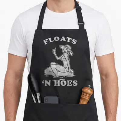 Trip floats apron - Distressed white woman on tube with FLOATS 'N HOES text — shown on a black cotton canvas apron against a white background
