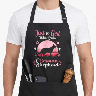 Retro german dog mom apron - Pink and white retro text Just a Girl Who Loves German Shepherd around sunset dog — shown on a black cotton canvas apron against a white background