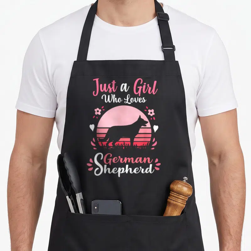 Retro german dog mom apron - Pink and white retro text Just a Girl Who Loves German Shepherd around sunset dog — shown on a black cotton canvas apron against a white background