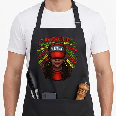 Queen history african american aprons - Cartoon woman in red cap with BLACK text surrounded by colorful affirming — shown on a black cotton canvas apron against a white background