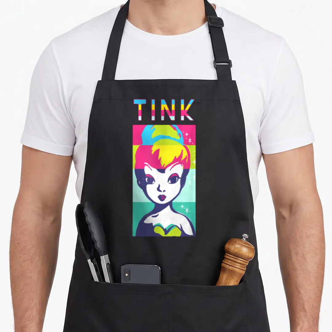Peter color block apron - TINK text above Tinker Bell portrait on blue yellow pink green stripes with scattered stars — shown on a black cotton canvas apron against a white background