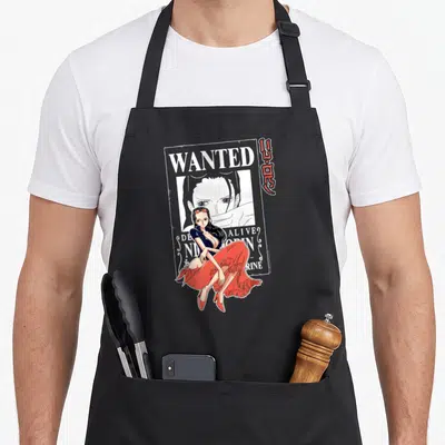 Robin anime apron - Seated woman in red skirt overlapping wanted poster with white and red text and vertical Japanese — shown on a black cotton canvas apron against a white background