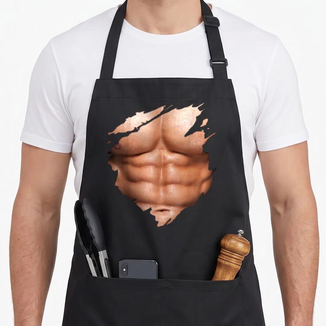 Chest six pack apron - Photo of muscular tan male torso framed by jagged ripped paper edges on black fabric — shown on a black cotton canvas apron against a white background