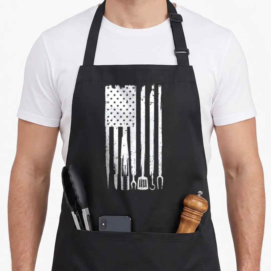 Fan barbecue apron - White distressed USA flag with tool handles replacing stripes on black apron — shown on a black cotton canvas apron against a white background