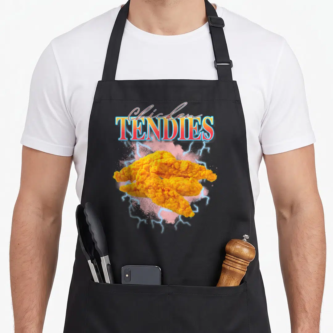 Tendy heavy metal apron - Golden brown chicken tendies under stacked text with pink cloud and blue lightning bolts — shown on a black cotton canvas apron against a white background
