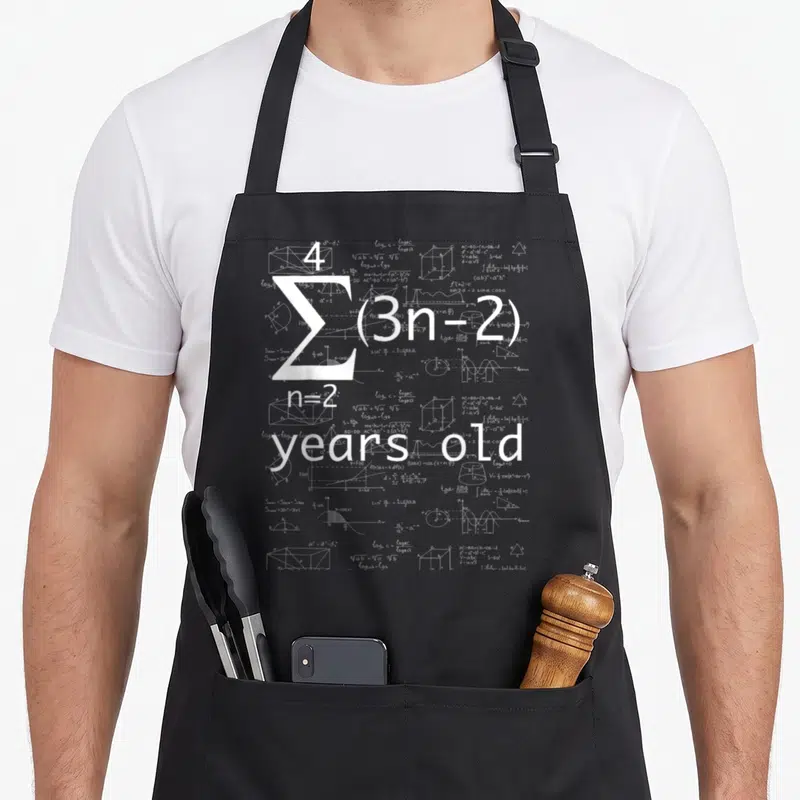 21st geek apron - White math formulas and 4 n=2 years old text overlaying equations — shown on a black cotton canvas apron against a white background