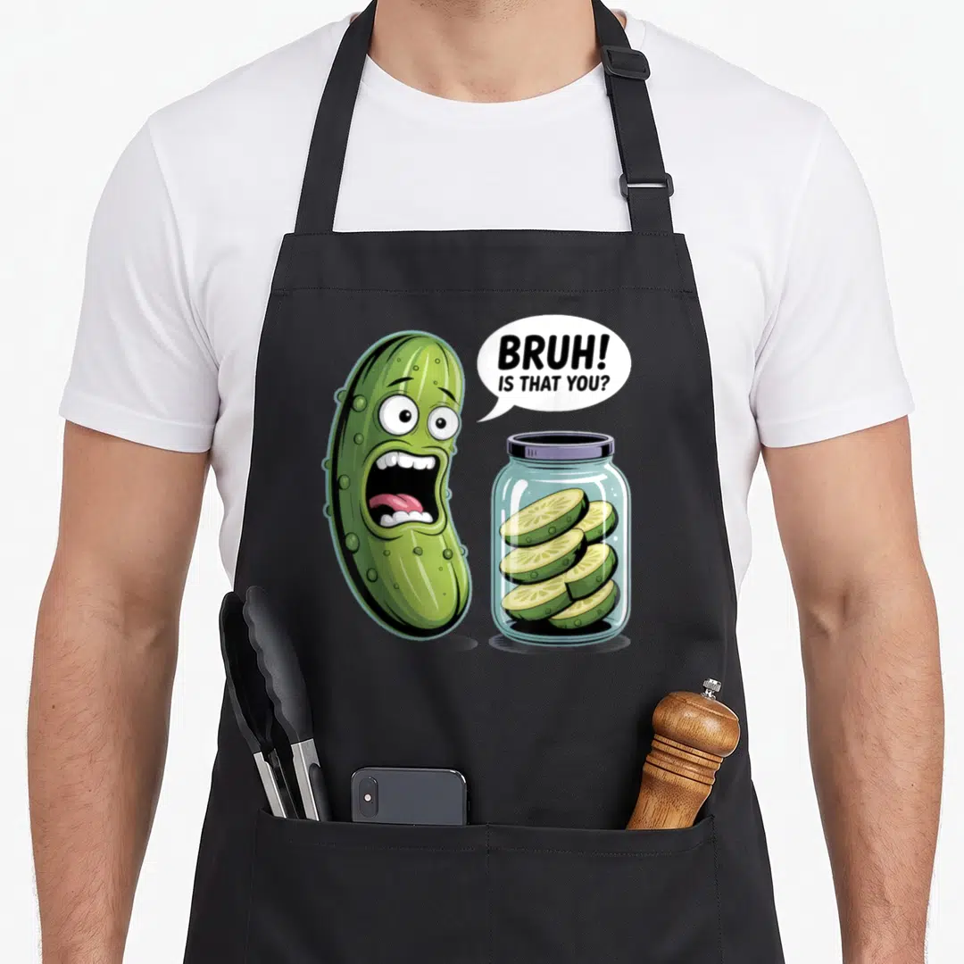 Pickling pickle apron - Shocked cartoon cucumber saying BRUH IS THAT YOU near a jar of pickle slices — shown on a black cotton canvas apron against a white background
