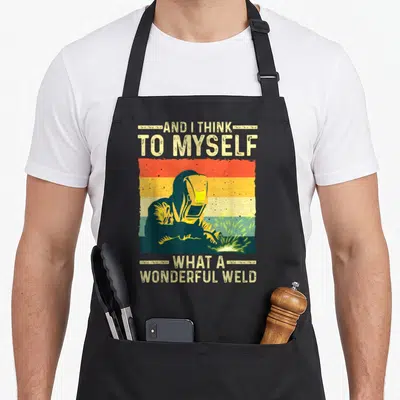 Welding blacksmith apron - Retro striped background with welder silhouette and text AND I THINK TO MYSELF WHAT — shown on a black cotton canvas apron against a white background