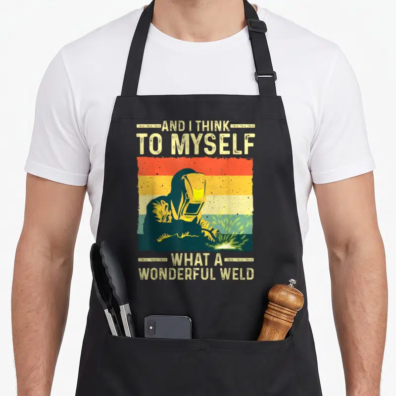 Welding blacksmith apron - Retro striped background with welder silhouette and text AND I THINK TO MYSELF WHAT — shown on a black cotton canvas apron against a white background