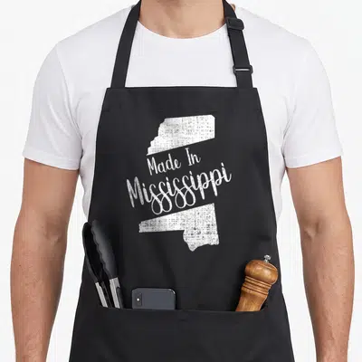 State mississippi river apron - White distressed Mississippi state map outline with Made In Mississippi text — shown on a black cotton canvas apron against a white background