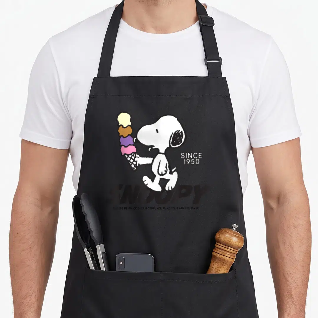 Cone ice cream apron - Snoopy holding a four scoop ice cream cone with SINCE 1950 text and a quote below — shown on a black cotton canvas apron against a white background