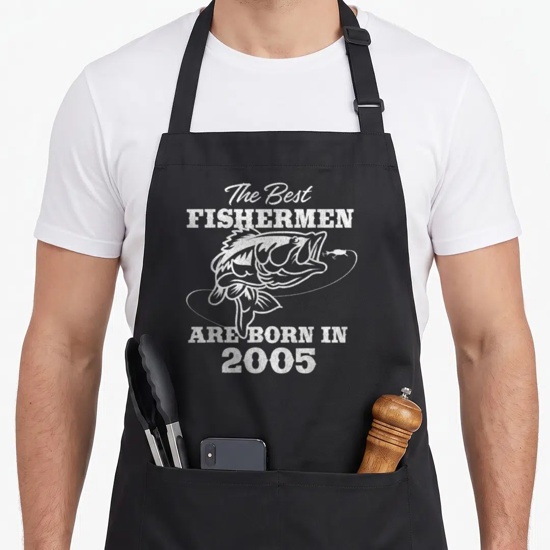 21st fishing aprons - White distressed fish with looping line and text The Best Fishermen Are Born In 2005 — shown on a black cotton canvas apron against a white background