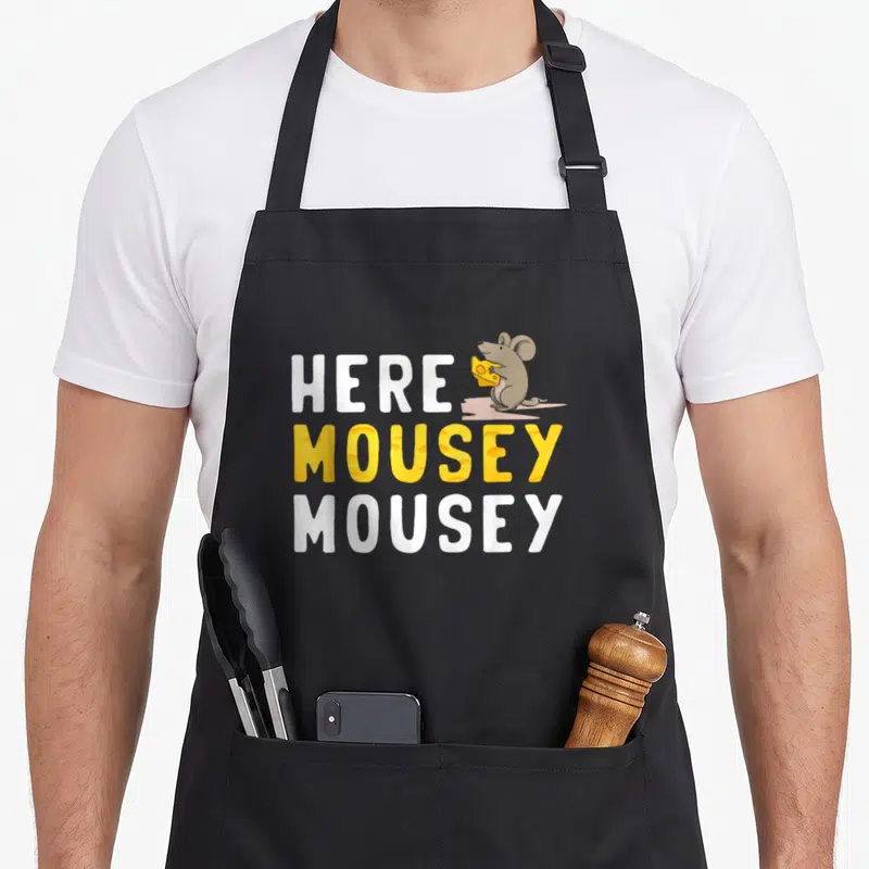 Mice cute mouse apron - Stacked Here Mousey Mousey text with cartoon mouse holding yellow cheese wedge — shown on a black cotton canvas apron against a white background