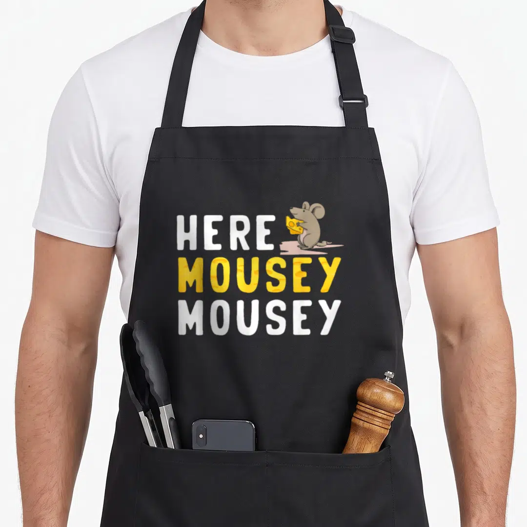 Mice cute mouse apron - Stacked Here Mousey Mousey text with cartoon mouse holding yellow cheese wedge — shown on a black cotton canvas apron against a white background