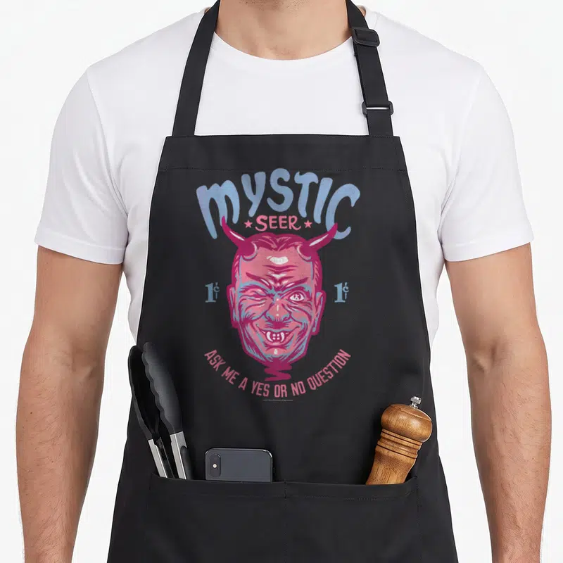 Twilight apron or apron - Retro pink and blue demon head with Mystic Seer text and yes or no question prompt — shown on a black cotton canvas apron against a white background