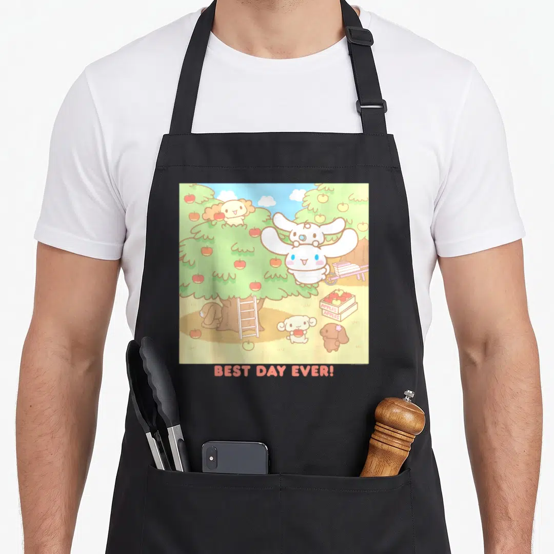 Cinnamoroll apple apron - Cartoon white and tan dogs picking apples under a tree with BEST DAY EVER! text — shown on a black cotton canvas apron against a white background
