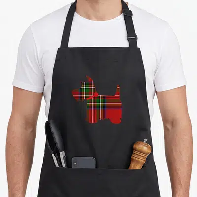 Scottie red plaid apron - Scottish Terrier silhouette filled with red tartan plaid and solid red collar — shown on a black cotton canvas apron against a white background